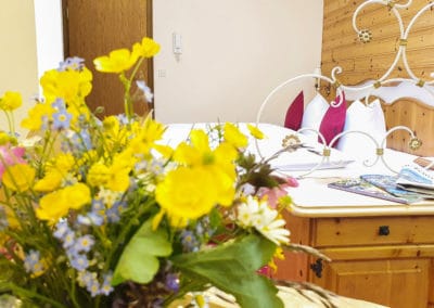 Haus Schmidt_Ferienwohnung2_Blumenstrauß und Blick zum Bett